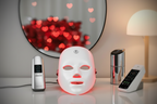 LED face mask on a table with heart-shaped lights in the background