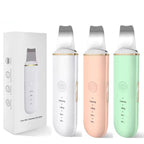 Set of three facial cleansing devices in white, pink, and green with packaging on a white background.